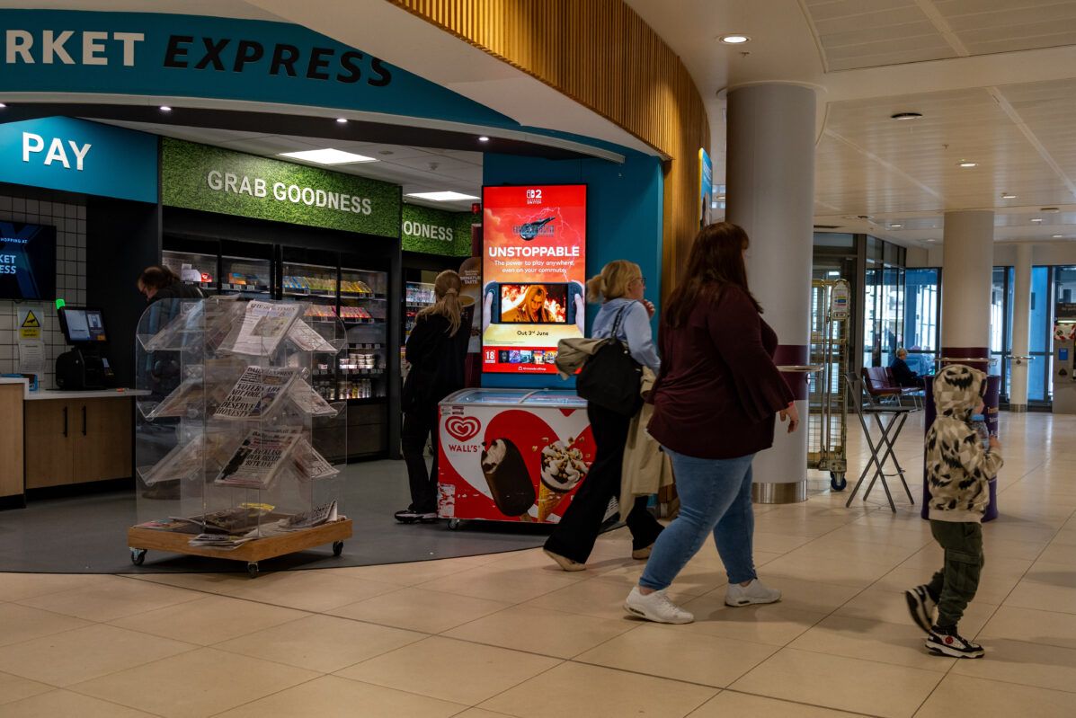 A digital screen in a hospital concourse beside a shop